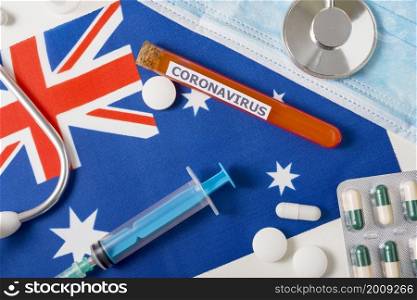 Coronavirus, nCoV concept. Top view protective breathing mask, stethoscope, syringe, pills on the flag of Australia. A new outbreak of the Chinese coronavirus. Coronavirus, nCoV concept. Top view protective breathing mask, stethoscope, syringe, pills on the flag of Australia.