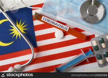 Coronavirus, nCoV concept. Top view protective breathing mask, stethoscope, syringe, pills on the flag of Malaysia. A new outbreak of the Chinese coronavirus. Coronavirus, nCoV concept. Top view protective breathing mask, stethoscope, syringe, pills on the flag of Malaysia.