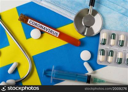 Coronavirus, nCoV concept. Top view protective breathing mask, stethoscope, syringe, pills on the flag of Sweden. A new outbreak of the Chinese coronavirus. Coronavirus, nCoV concept. Top view protective breathing mask, stethoscope, syringe, pills on the flag of Sweden.