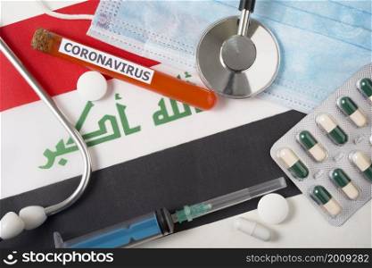 Coronavirus, nCoV concept. Top view protective breathing mask, stethoscope, syringe, pills on the flag of Iraq. A new outbreak of the Chinese coronavirus. Coronavirus, nCoV concept. Top view protective breathing mask, stethoscope, syringe, pills on the flag of Iraq.