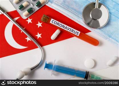 Coronavirus, nCoV concept. Top view protective breathing mask, stethoscope, syringe, pills on the flag of Singapore. A new outbreak of the Chinese coronavirus. Coronavirus, nCoV concept. Top view protective breathing mask, stethoscope, syringe, pills on the flag of Singapore.