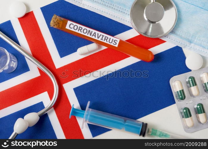 Coronavirus, nCoV concept. Top view protective breathing mask, stethoscope, syringe, pills on the flag of Iceland. A new outbreak of the Chinese coronavirus. Coronavirus, nCoV concept. Top view protective breathing mask, stethoscope, syringe, pills on the flag of Iceland.