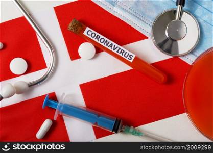 Coronavirus, nCoV concept. Top view protective breathing mask, stethoscope, syringe, pills on the flag of Denmark. A new outbreak of the Chinese coronavirus. Coronavirus, nCoV concept. Top view protective breathing mask, stethoscope, syringe, pills on the flag of Denmark.