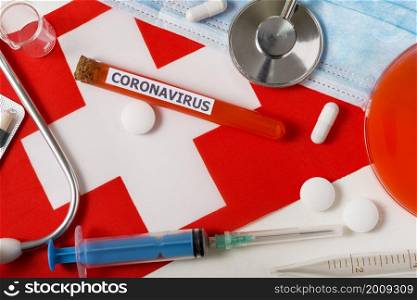Coronavirus, nCoV concept. Top view protective breathing mask, stethoscope, syringe, pills on the flag of Switzerland. A new outbreak of the Chinese coronavirus. Coronavirus, nCoV concept. Top view protective breathing mask, stethoscope, syringe, pills on the flag of Switzerland.