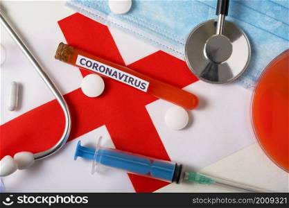 Coronavirus, nCoV concept. Top view protective breathing mask, stethoscope, syringe, pills on the flag of England. A new outbreak of the Chinese coronavirus. Coronavirus, nCoV concept. Top view protective breathing mask, stethoscope, syringe, pills on the flag of England.