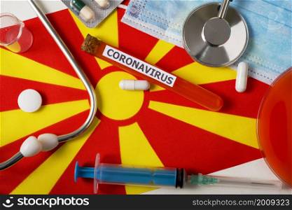Coronavirus, nCoV concept. Top view protective breathing mask, stethoscope, syringe, pills on the flag of North Macedonia. A new outbreak of the Chinese coronavirus. Coronavirus, nCoV concept. Top view protective breathing mask, stethoscope, syringe, pills on the flag of North Macedonia.