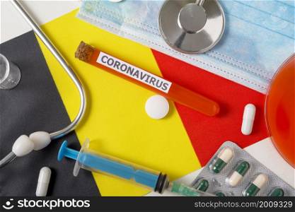 Coronavirus, nCoV concept. Top view protective breathing mask, stethoscope, syringe, pills on the flag of Belgium. A new outbreak of the Chinese coronavirus. Coronavirus, nCoV concept. Top view protective breathing mask, stethoscope, syringe, pills on the flag of Belgium.
