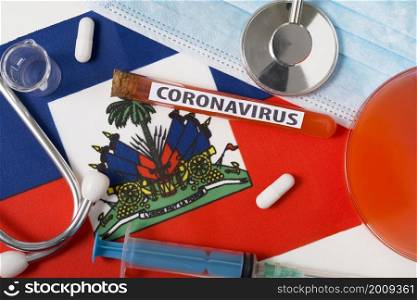 Coronavirus, nCoV concept. Top view protective breathing mask, stethoscope, syringe, pills on the flag of Haiti. A new outbreak of the Chinese coronavirus. Coronavirus, nCoV concept. Top view protective breathing mask, stethoscope, syringe, pills on the flag of Haiti.