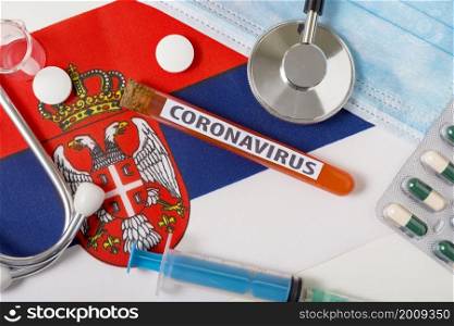 Coronavirus, nCoV concept. Top view protective breathing mask, stethoscope, syringe, tablets on the flag of Serbia. A new outbreak of the Chinese coronavirus. Coronavirus, nCoV concept. Top view protective breathing mask, stethoscope, syringe, tablets on the flag of Serbia.