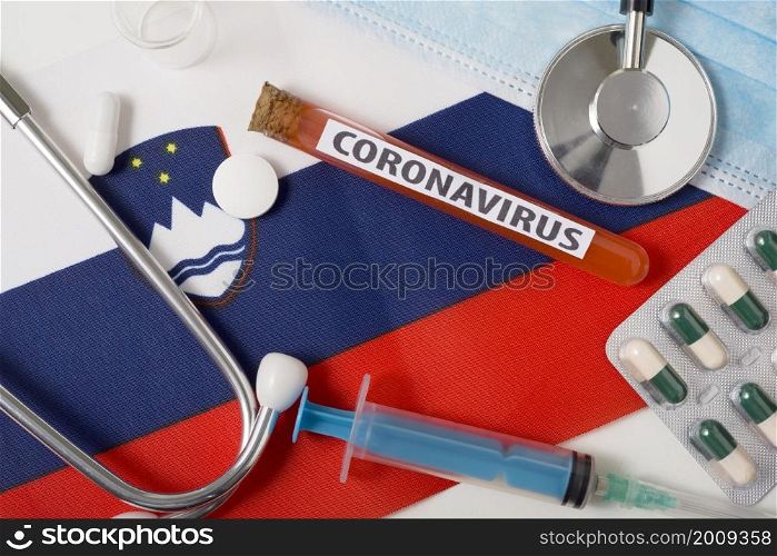 Coronavirus, nCoV concept. Top view protective breathing mask, stethoscope, syringe, tablets on the flag of Slovenia. A new outbreak of the Chinese coronavirus. Coronavirus, nCoV concept. Top view protective breathing mask, stethoscope, syringe, tablets on the flag of Slovenia.