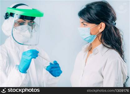 Coronavirus test. Medical worker in protective suite taking a swab for corona virus test, potentially infected young woman