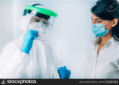 Coronavirus test. Medical worker in protective suite taking a swab for corona virus test, potentially infected young woman