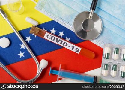 Coronavirus, the concept COVid-19. A protective breathing mask, stethoscope, syringe, and pills on the flag of Venezuela are visible from above . A new outbreak of the Chinese coronavirus. Coronavirus, the concept COVid-19. A protective breathing mask, stethoscope, syringe, and pills on the flag of Venezuela are visible from above .
