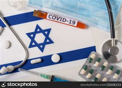 Coronavirus, the concept COVid-19. Top view of a protective breathing mask, stethoscope, syringe, pills on the flag of Israel. A new outbreak of the Chinese coronavirus. Coronavirus, the concept COVid-19. Top view of a protective breathing mask, stethoscope, syringe, pills on the flag of Israel.