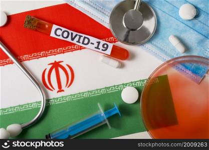 Coronavirus, the concept COVid-19. Top view of a protective breathing mask, stethoscope, syringe, pills on the flag of Iran. A new outbreak of the Chinese coronavirus. Coronavirus, the concept COVid-19. Top view of a protective breathing mask, stethoscope, syringe, pills on the flag of Iran.