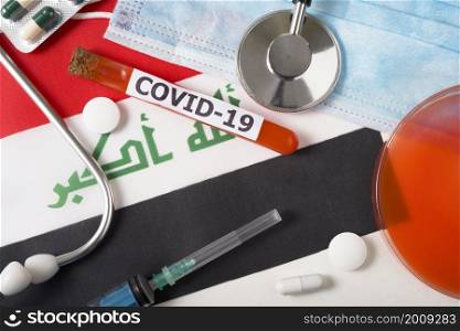 Coronavirus, the concept COVid-19. Top view of a protective breathing mask, stethoscope, syringe, pills on the flag of Iraq. A new outbreak of the Chinese coronavirus. Coronavirus, the concept COVid-19. Top view of a protective breathing mask, stethoscope, syringe, pills on the flag of Iraq.