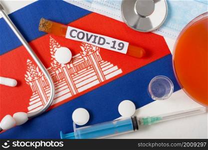 Coronavirus, the concept COVid-19. Top view of a protective breathing mask, stethoscope, syringe, pills on the flag of Cambodia. A new outbreak of the Chinese coronavirus. Coronavirus, the concept COVid-19. Top view of a protective breathing mask, stethoscope, syringe, pills on the flag of Cambodia.