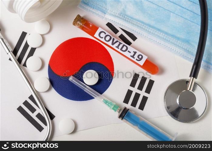 Coronavirus, the concept COVid-19. Top view protective breathing mask, stethoscope, syringe, pills on the flag of South Korea. A new outbreak of the Chinese coronavirus. Coronavirus, the concept COVid-19. Top view protective breathing mask, stethoscope, syringe, pills on the flag of South Korea.