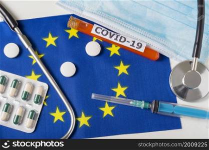 Coronavirus, the concept COVid-19. Top view protective breathing mask, stethoscope, syringe, pills on the flag of Europe. A new outbreak of the Chinese coronavirus. Coronavirus, the concept COVid-19. Top view protective breathing mask, stethoscope, syringe, pills on the flag of Europe.