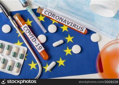 Coronavirus, the concept COVid-19. Top view protective breathing mask, stethoscope, syringe, pills on the flag of Europe. A new outbreak of the Chinese coronavirus. Coronavirus, the concept COVid-19. Top view protective breathing mask, stethoscope, syringe, pills on the flag of Europe.