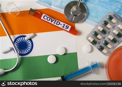 Coronavirus, the concept COVid-19. Top view protective breathing mask, stethoscope, syringe, pills on the flag of India. A new outbreak of the Chinese coronavirus. Coronavirus, the concept COVid-19. Top view protective breathing mask, stethoscope, syringe, pills on the flag of India.
