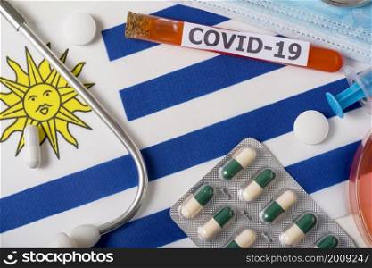Coronavirus, the concept COVid-19. Top view protective breathing mask, stethoscope, syringe, pills on the flag of Uruguay. A new outbreak of the Chinese coronavirus. Coronavirus, the concept COVid-19. Top view protective breathing mask, stethoscope, syringe, pills on the flag of Uruguay.