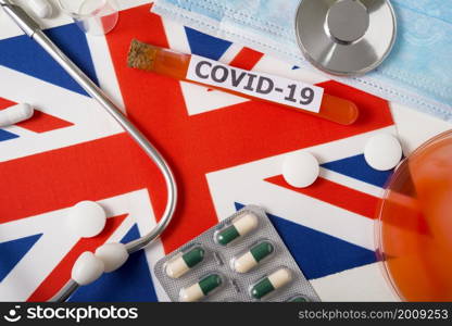 Coronavirus, the concept COVid-19. Top view protective breathing mask, stethoscope, syringe, pills on the flag of great Britain. A new outbreak of the Chinese coronavirus. Coronavirus, the concept COVid-19. Top view protective breathing mask, stethoscope, syringe, pills on the flag of great Britain.