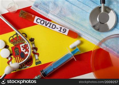 Coronavirus, the concept COVid-19. Top view protective breathing mask, stethoscope, syringe, pills on the flag of Spain. A new outbreak of the Chinese coronavirus. Coronavirus, the concept COVid-19. Top view protective breathing mask, stethoscope, syringe, pills on the flag of Spain.