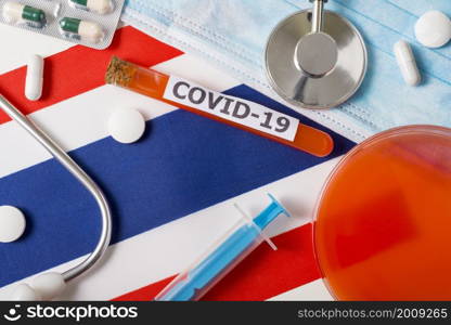 Coronavirus, the concept COVid-19. Top view protective breathing mask, stethoscope, syringe, pills on the flag of Thailand. A new outbreak of the Chinese coronavirus. Coronavirus, the concept COVid-19. Top view protective breathing mask, stethoscope, syringe, pills on the flag of Thailand.