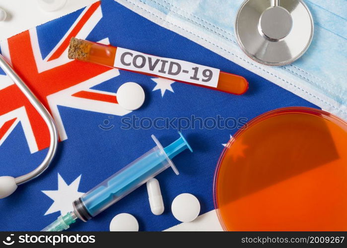 Coronavirus, the concept COVid-19. Top view protective breathing mask, stethoscope, syringe, pills on the flag of Australia. A new outbreak of the Chinese coronavirus. Coronavirus, the concept COVid-19. Top view protective breathing mask, stethoscope, syringe, pills on the flag of Australia.