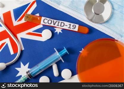 Coronavirus, the concept COVid-19. Top view protective breathing mask, stethoscope, syringe, pills on the flag of Australia. A new outbreak of the Chinese coronavirus. Coronavirus, the concept COVid-19. Top view protective breathing mask, stethoscope, syringe, pills on the flag of Australia.