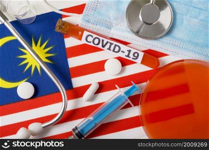 Coronavirus, the concept COVid-19. Top view protective breathing mask, stethoscope, syringe, pills on the flag of Malaysia. A new outbreak of the Chinese coronavirus. Coronavirus, the concept COVid-19. Top view protective breathing mask, stethoscope, syringe, pills on the flag of Malaysia.