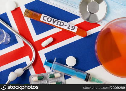 Coronavirus, the concept COVid-19. Top view protective breathing mask, stethoscope, syringe, pills on the flag of Iceland. A new outbreak of the Chinese coronavirus. Coronavirus, the concept COVid-19. Top view protective breathing mask, stethoscope, syringe, pills on the flag of Iceland.