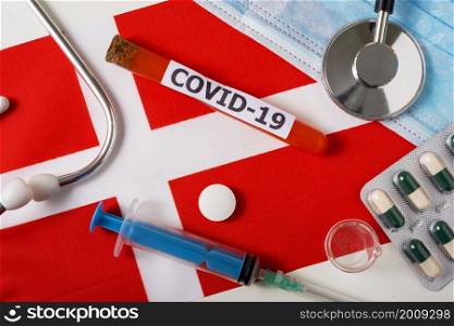 Coronavirus, the concept COVid-19. Top view protective breathing mask, stethoscope, syringe, pills on the flag of Denmark. A new outbreak of the Chinese coronavirus. Coronavirus, the concept COVid-19. Top view protective breathing mask, stethoscope, syringe, pills on the flag of Denmark.