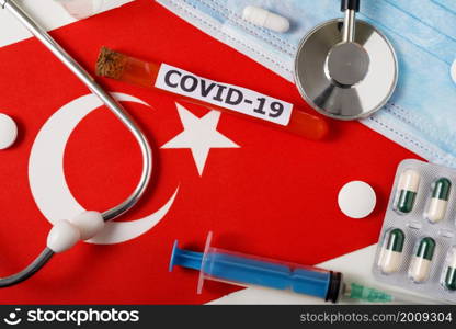 Coronavirus, the concept COVid-19. Top view protective breathing mask, stethoscope, syringe, pills on the flag of Turkey. A new outbreak of the Chinese coronavirus. Coronavirus, the concept COVid-19. Top view protective breathing mask, stethoscope, syringe, pills on the flag of Turkey.