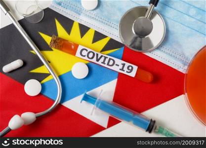 Coronavirus, the concept COVid-19. Top view protective breathing mask, stethoscope, syringe, pills on the flag of Antigua and Barbuda. A new outbreak of the Chinese coronavirus. Coronavirus, the concept COVid-19. Top view protective breathing mask, stethoscope, syringe, pills on the flag of Antigua and Barbuda.