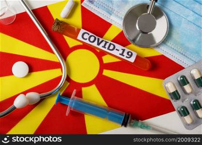 Coronavirus, the concept COVid-19. Top view protective breathing mask, stethoscope, syringe, pills on the flag of North Macedonia. A new outbreak of the Chinese coronavirus. Coronavirus, the concept COVid-19. Top view protective breathing mask, stethoscope, syringe, pills on the flag of North Macedonia.