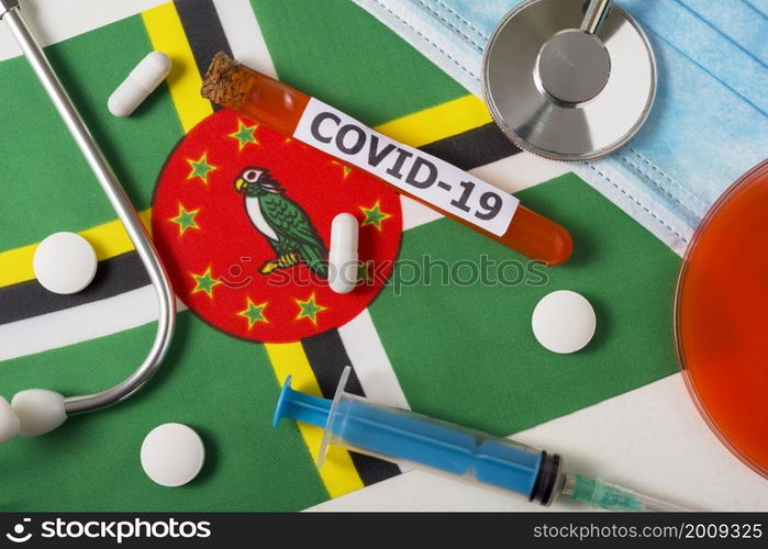 Coronavirus, the concept COVid-19. Top view protective breathing mask, stethoscope, syringe, pills on the flag of Dominica. A new outbreak of the Chinese coronavirus. Coronavirus, the concept COVid-19. Top view protective breathing mask, stethoscope, syringe, pills on the flag of Dominica.