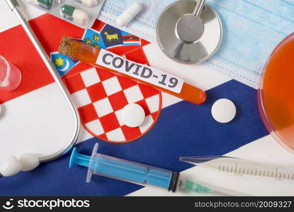 Coronavirus, the concept COVid-19. Top view protective breathing mask, stethoscope, syringe, pills on the flag of Croatia. A new outbreak of the Chinese coronavirus. Coronavirus, the concept COVid-19. Top view protective breathing mask, stethoscope, syringe, pills on the flag of Croatia.