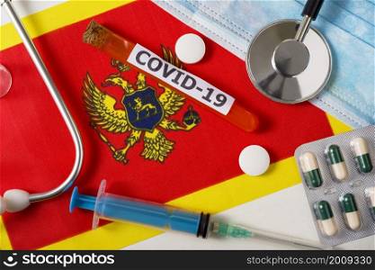 Coronavirus, the concept COVid-19. Top view protective breathing mask, stethoscope, syringe, pills on the flag of Montenegro. A new outbreak of the Chinese coronavirus. Coronavirus, the concept COVid-19. Top view protective breathing mask, stethoscope, syringe, pills on the flag of Montenegro.