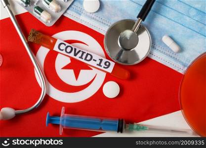 Coronavirus, the concept COVid-19. Top view protective breathing mask, stethoscope, syringe, pills on the flag of Tunisia. A new outbreak of the Chinese coronavirus. Coronavirus, the concept COVid-19. Top view protective breathing mask, stethoscope, syringe, pills on the flag of Tunisia.