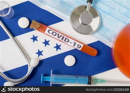 Coronavirus, the concept COVid-19. Top view protective breathing mask, stethoscope, syringe, pills on the flag of Honduras. A new outbreak of the Chinese coronavirus. Coronavirus, the concept COVid-19. Top view protective breathing mask, stethoscope, syringe, pills on the flag of Honduras.