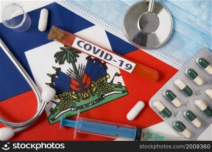 Coronavirus, the concept COVid-19. Top view protective breathing mask, stethoscope, syringe, pills on the flag of Haiti. A new outbreak of the Chinese coronavirus. Coronavirus, the concept COVid-19. Top view protective breathing mask, stethoscope, syringe, pills on the flag of Haiti.