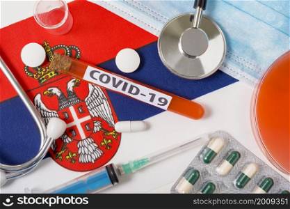 Coronavirus, the concept COVid-19. Top view protective breathing mask, stethoscope, syringe, tablets on the flag of Serbia. A new outbreak of the Chinese coronavirus. Coronavirus, the concept COVid-19. Top view protective breathing mask, stethoscope, syringe, tablets on the flag of Serbia.