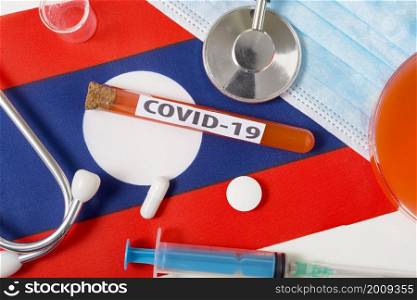 Coronavirus, the concept COVid-19. Top view protective breathing mask, stethoscope, syringe, tablets on the flag of Laos. A new outbreak of the Chinese coronavirus. Coronavirus, the concept COVid-19. Top view protective breathing mask, stethoscope, syringe, tablets on the flag of Laos.