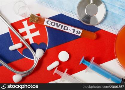 Coronavirus, the concept COVid-19. Top view protective breathing mask, stethoscope, syringe, tablets on the flag of Slovakia. A new outbreak of the Chinese coronavirus. Coronavirus, the concept COVid-19. Top view protective breathing mask, stethoscope, syringe, tablets on the flag of Slovakia.
