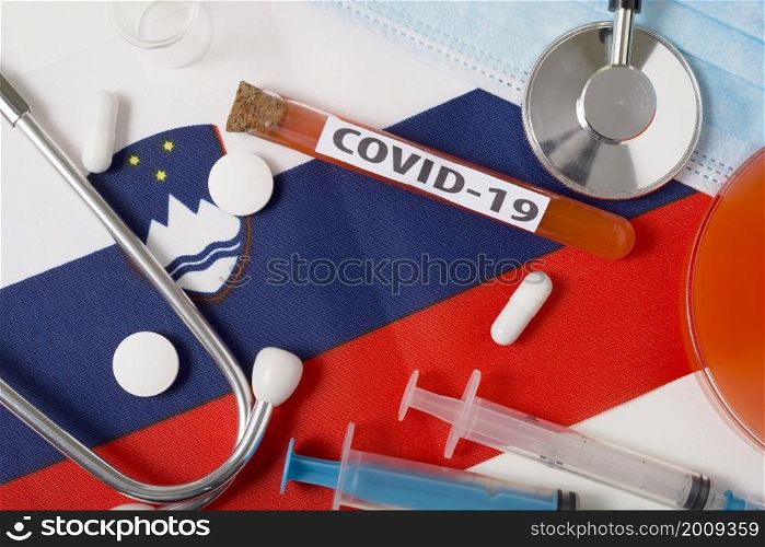 Coronavirus, the concept COVid-19. Top view protective breathing mask, stethoscope, syringe, tablets on the flag of Slovenia. A new outbreak of the Chinese coronavirus. Coronavirus, the concept COVid-19. Top view protective breathing mask, stethoscope, syringe, tablets on the flag of Slovenia.
