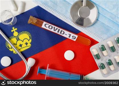 Coronavirus, the concept COVid-19. Top view protective breathing mask, stethoscope, syringe, tablets on the flag of Liechtenstein. A new outbreak of the Chinese coronavirus. Coronavirus, the concept COVid-19. Top view protective breathing mask, stethoscope, syringe, tablets on the flag of Liechtenstein.