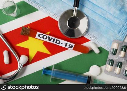 Coronavirus, the concept COVid-19. Top view protective breathing mask, stethoscope, syringe, tablets on the flag of Suriname. A new outbreak of the Chinese coronavirus. Coronavirus, the concept COVid-19. Top view protective breathing mask, stethoscope, syringe, tablets on the flag of Suriname.