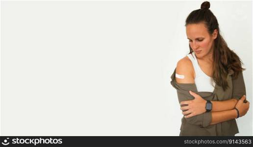 Coronavirus vaccination advertisement. Vaccinated woman showing arm with plaster bandage after Covid-19 vaccine injection. Concept of recommended inoculation, vaccination, vaccinated patient, vaccine. Panorama, free space for text, copy space.